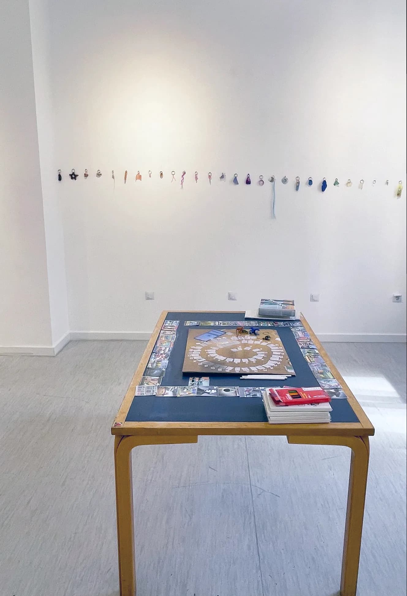 Table with a spiral board game beneath a long row of small hanging trinkets and charms