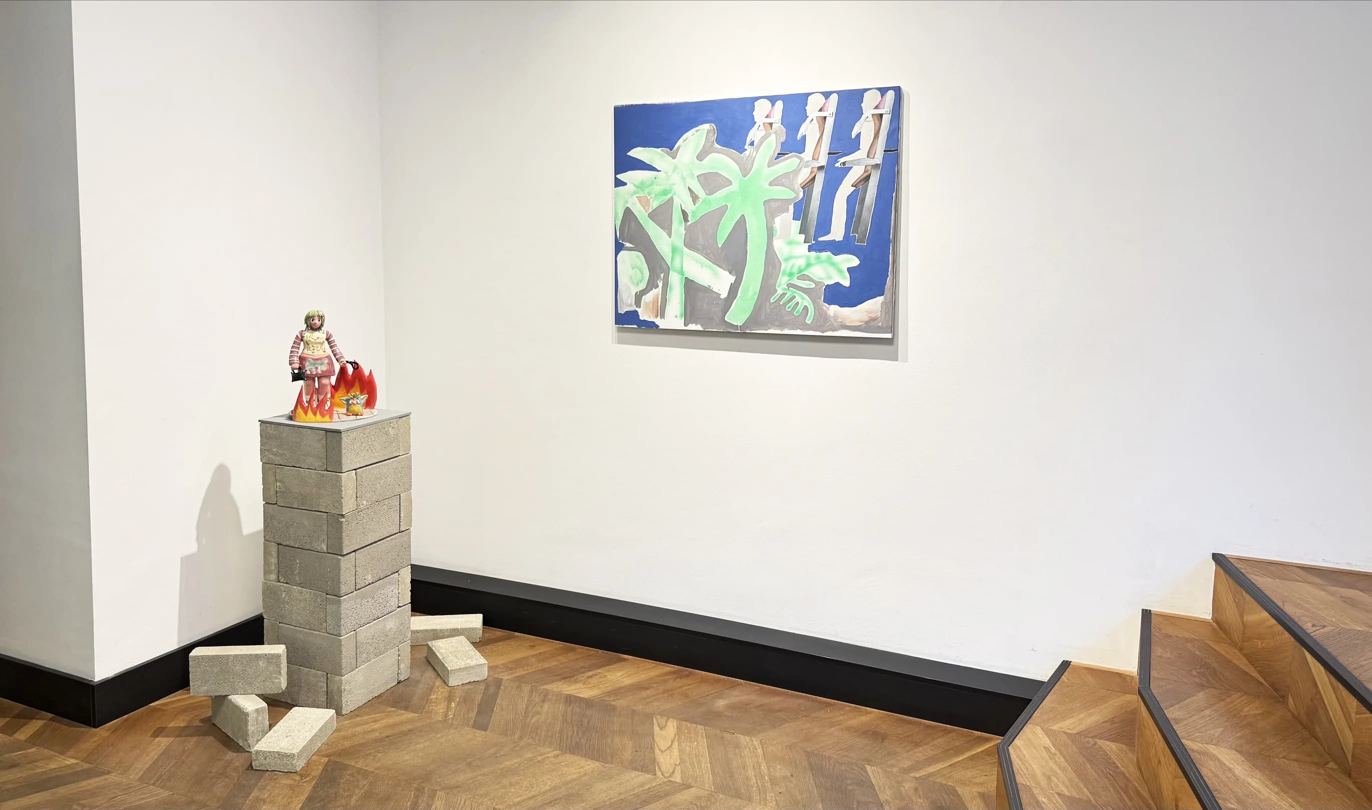A glazed figure on a stack of concrete bricks beneath a painting of palm trees