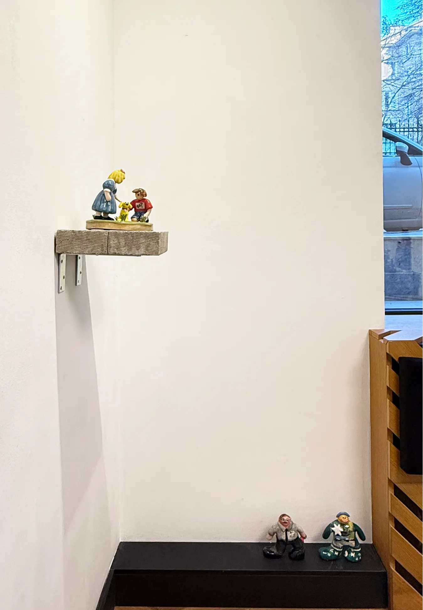 Floating stone shelf holding the girl-and-dog figure, with two more figures on a bench below