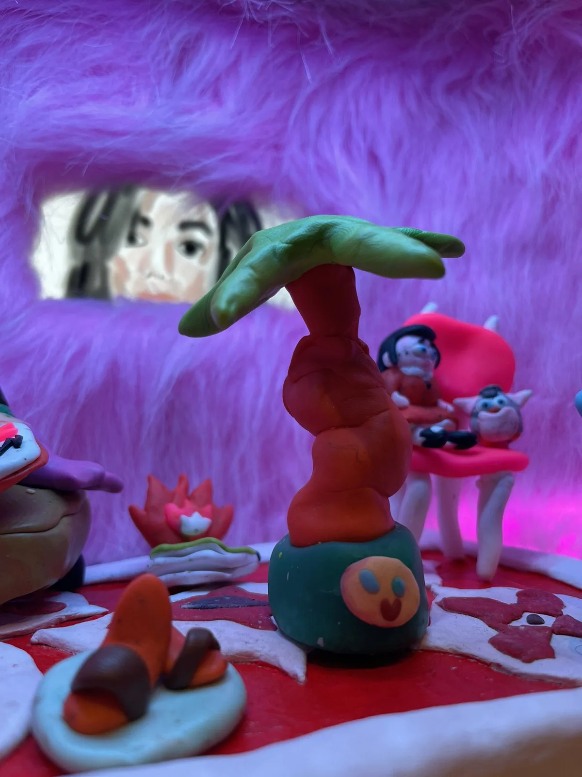 Clay palm tree in front of the fur wall's window, where a drawn face looks in