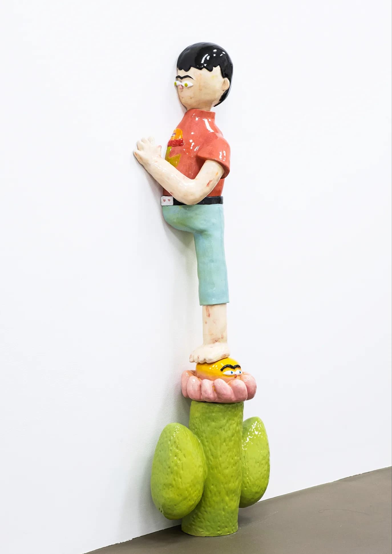 Detail of a ceramic figure of a boy climbing the wall, standing on a pink flower atop a cactus base