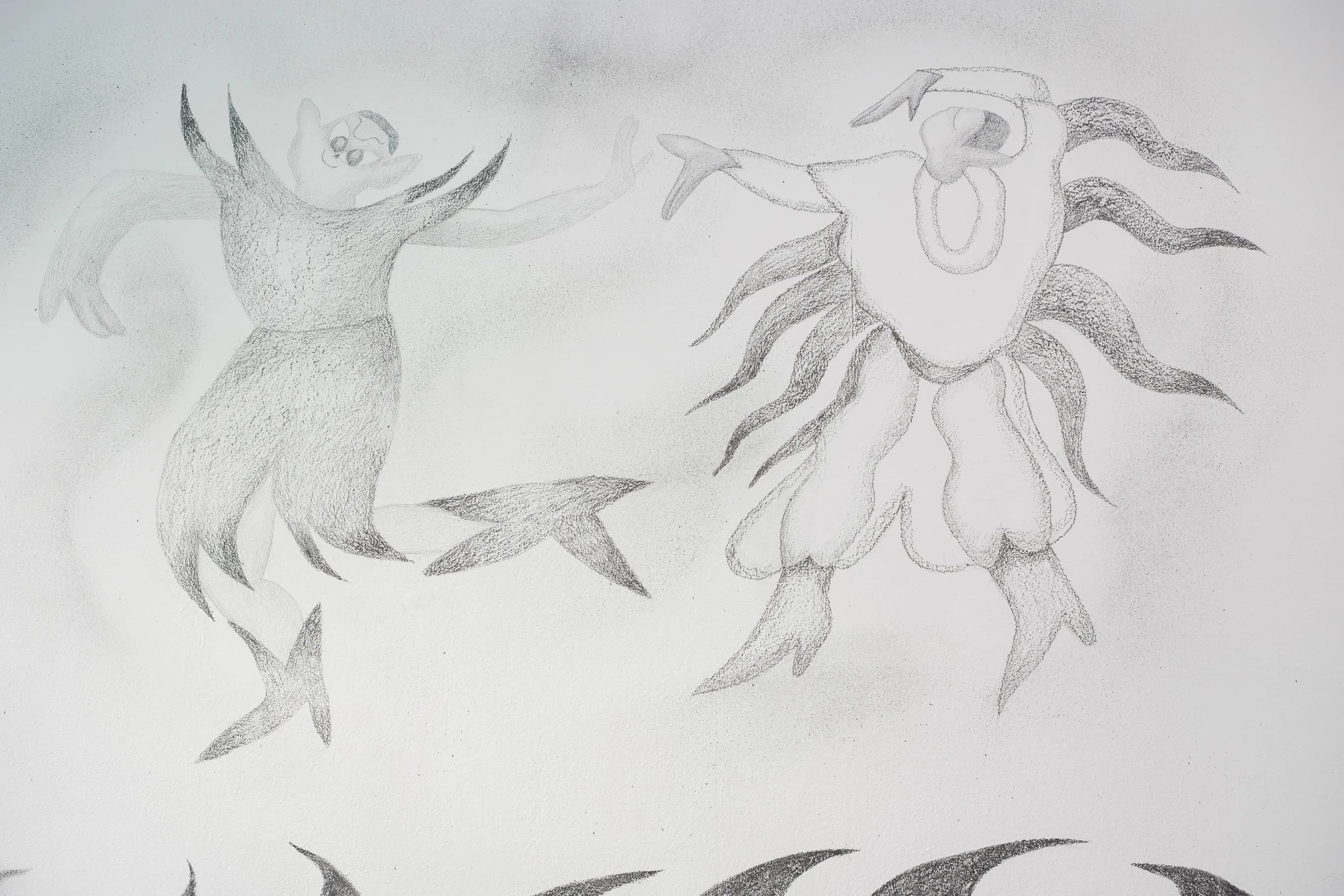Detail of the graphite wall drawing of two dancing masked figures