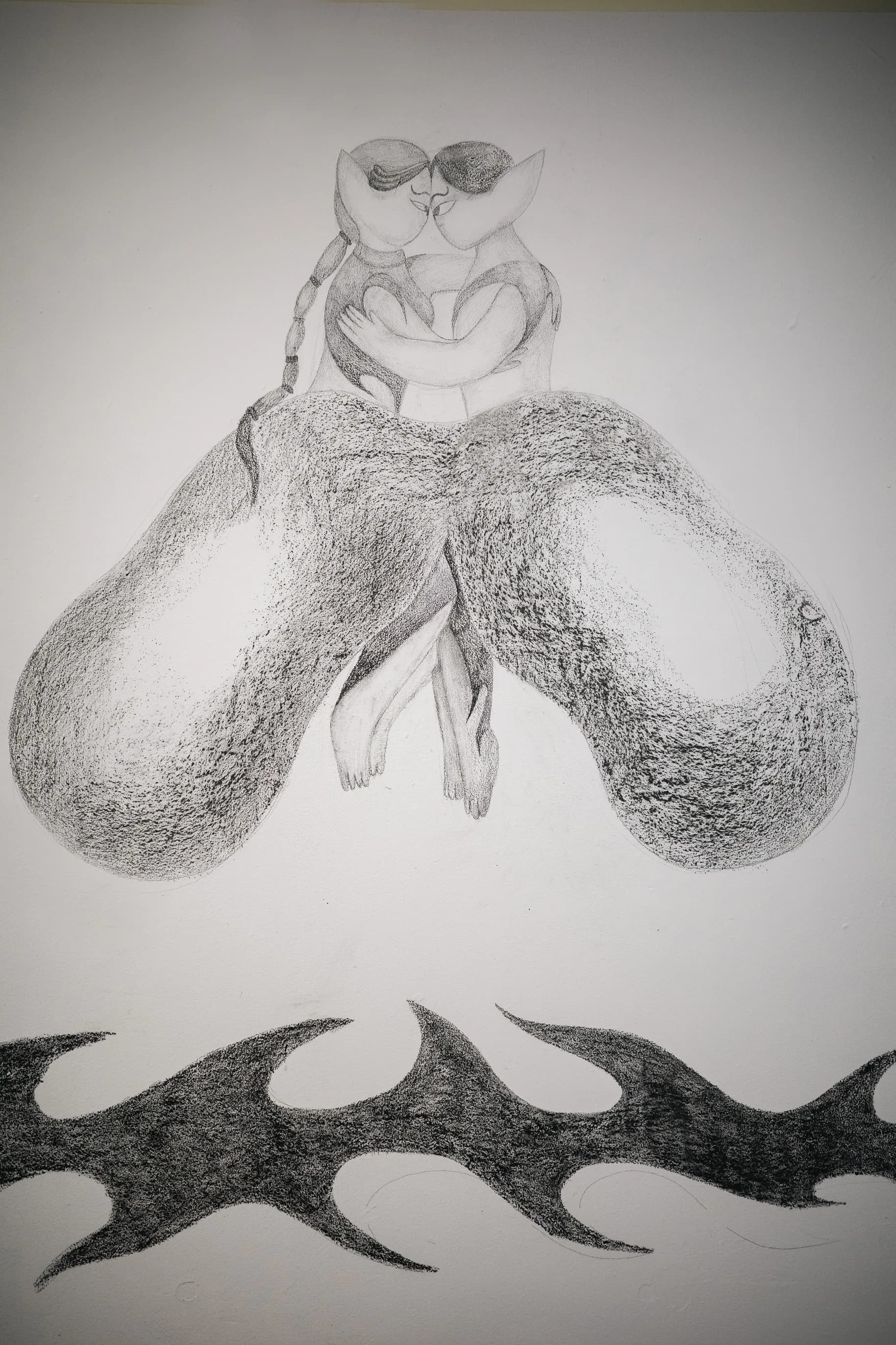Graphite wall drawing of two embracing figures above a thorn-vine motif