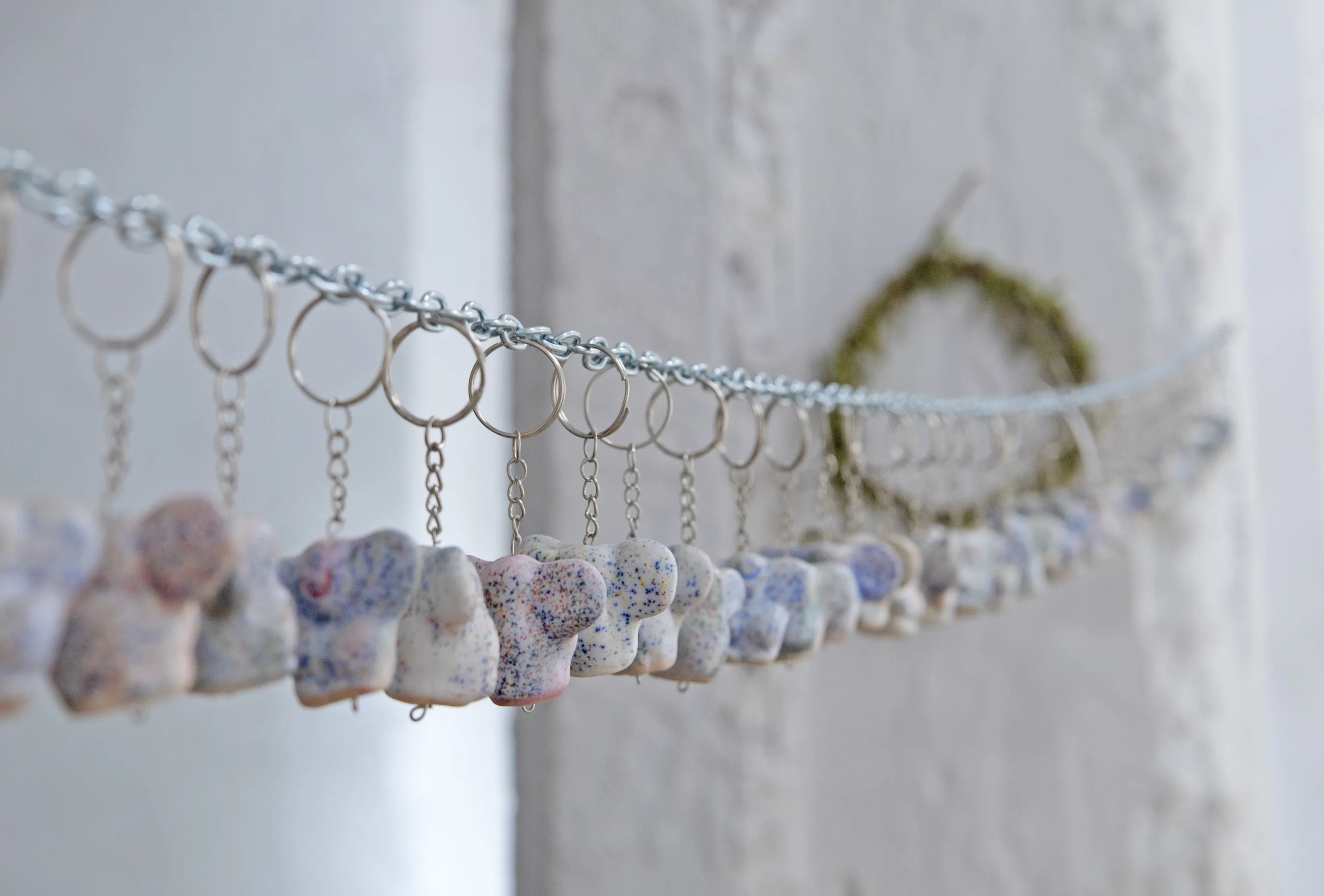 A chain strung across the room with small speckled ceramic keyrings hanging from it