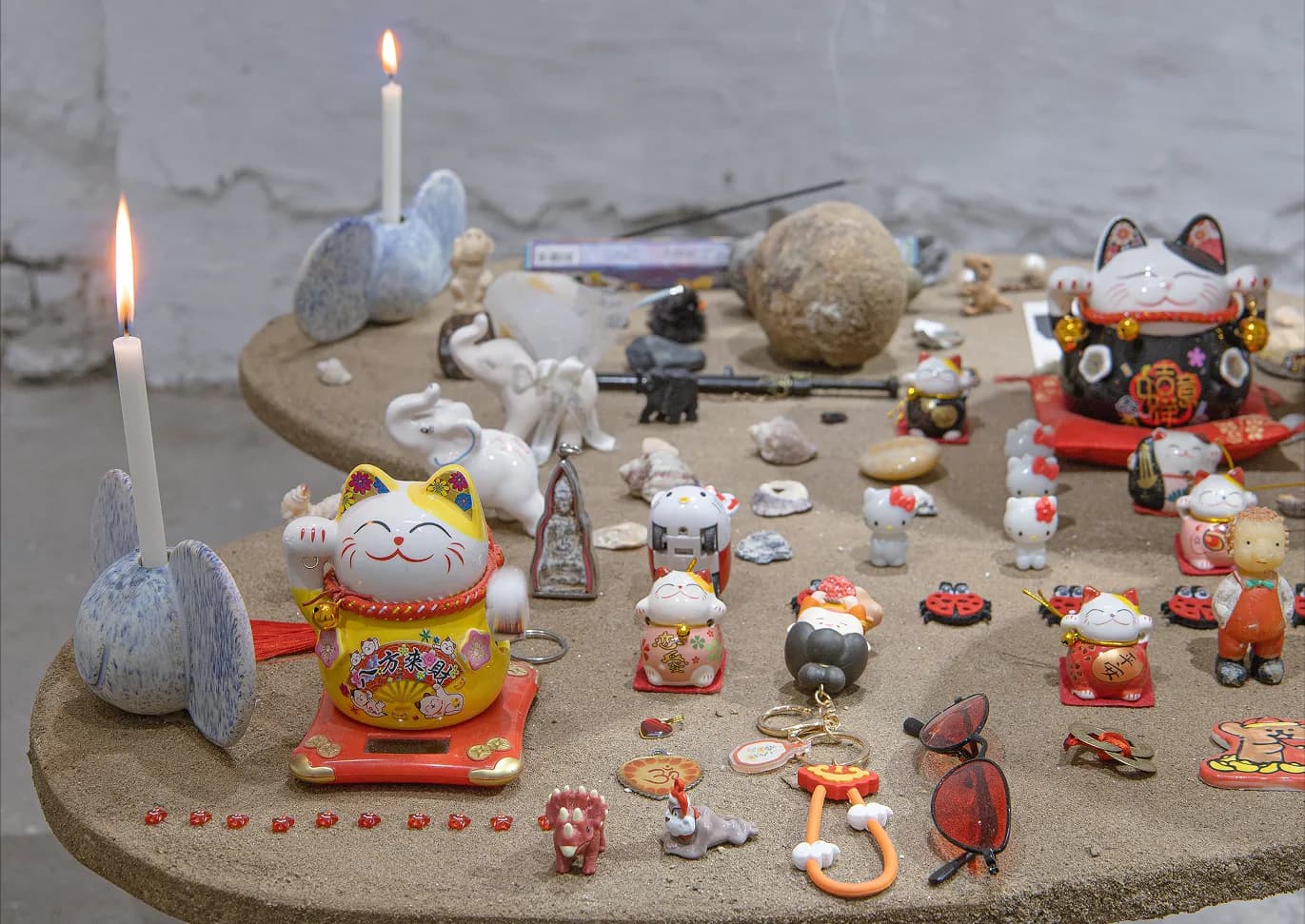Detail of lucky cat figurines, small toys and stones arranged on the altar table