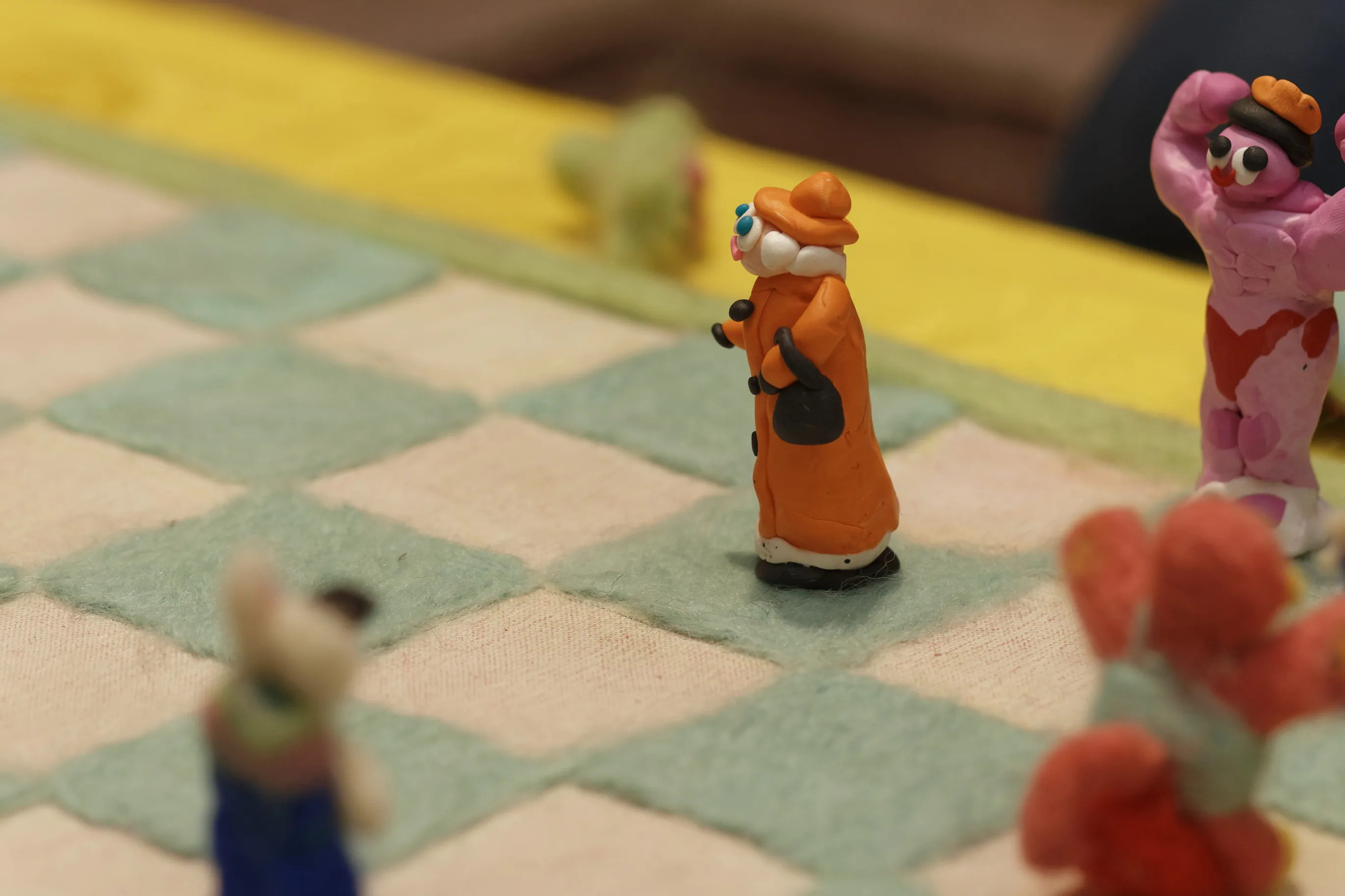 Close-up of a clay chess piece in an orange coat on the felt board