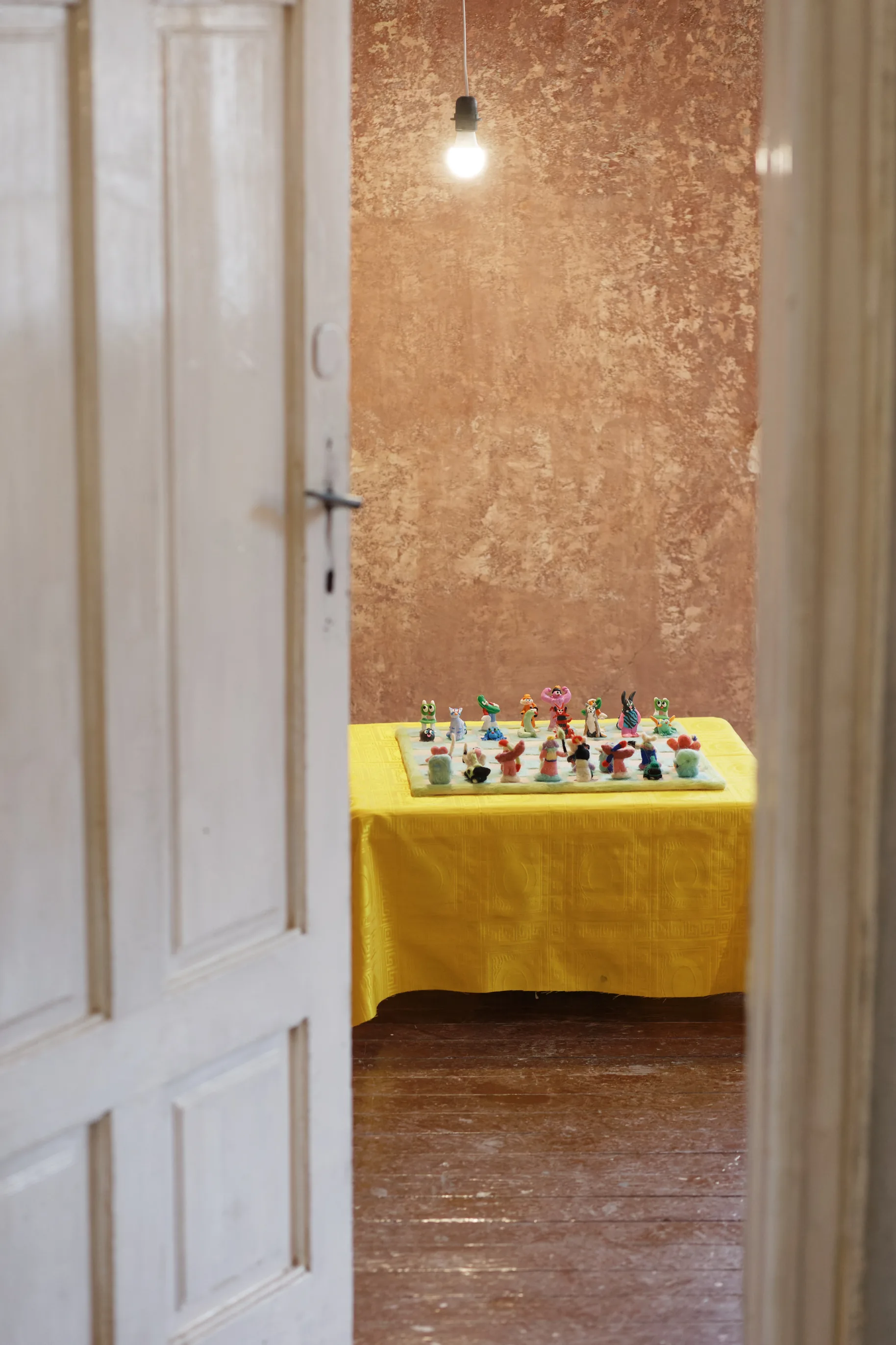 View through an open door of the yellow table with the felt chessboard and clay pieces
